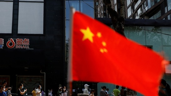 A China's flag flutters near people lining up to get tested at a makeshift nucleic acid testing site. (File image)(REUTERS)