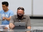 People use an Apple laptop computer and an Apple iPad in Manhattan, New York City.