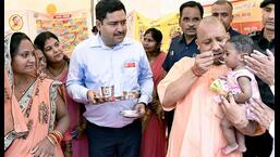 Uttar Pradesh chief minister Yogi Adityanath feeds a child as he inaugurates an employment fair in Gorakhpur. (ANI Photo)