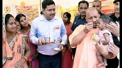 Uttar Pradesh chief minister Yogi Adityanath feeds a child as he inaugurates an employment fair in Gorakhpur. (ANI Photo)