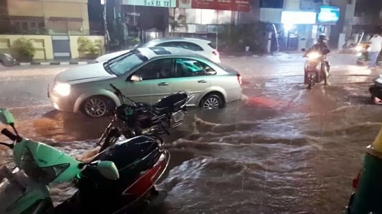 Vehicle ply on flooded street following heavy rainfall, in Bengaluru on Tuesday. (ANI)