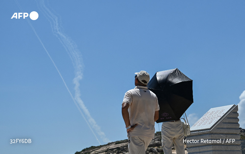 Tourists on Pingtan Island look at the smoke trail from Chinese projectiles. (AFP Twitter) Tourists on Pingtan Island look at the smoke trail from Chinese projectiles. (AFP Twitter)
