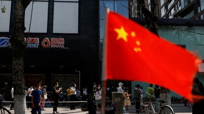 A China's flag flutters near people lining up to get tested at a makeshift nucleic acid testing site. (File image) (REUTERS)