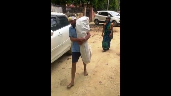 Video grab of Bajrangi carrying dad son’s body on shoulder amidst rain in Prayagraj. (HT PHOTO)