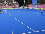 The technical delegate on the sidelines (in blue, left) has her hand held up with players in position.