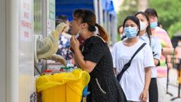 Um profissional de saúde coleta uma amostra de uma mulher para ser testada para Covid-19 em um local de coleta em Guangzhou, na província de Guangdong, no sul da China.  (AFP)