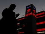 A girl checks her mobile phone as she walks past the Bharti Airtel office building in Gurugram, on the outskirts of New Delhi.