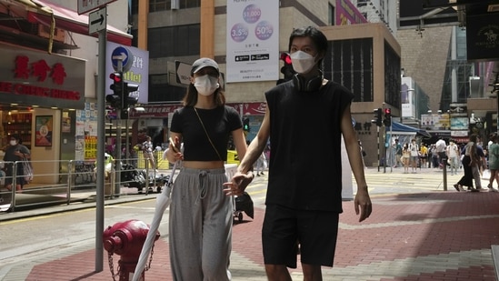 A couple wearing face masks walk along a street in Mongkok, a shopping district of Hong Kong. A couple wearing face masks walk along a street in Mongkok, a shopping district of Hong Kong. 