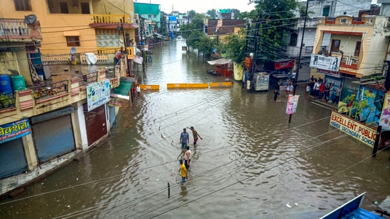 &nbsp;Locals wade through a waterlogged street following incessant monsoon rains, in Indore.(PTI)