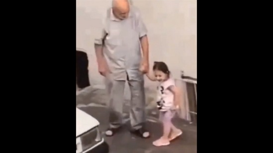 The cute little granddaughter and her grandfather can be seen enjoying the rain together. (Twitter/@GoodNewsCorres1)
