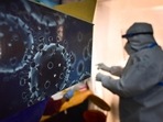 An illustration of the novel coronavirus seen next to a health care worker at a Covid-19 testing centre in New Delhi.