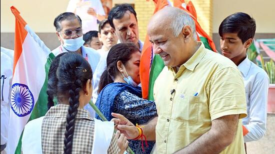 Delhi deputy chief minister Manish Sisodia hands out the tricolour to a student during a programme under “Har Hath Tiranga” campaign at Shahid Captain Amit Verma School, Inderpuri on Friday (ANI)