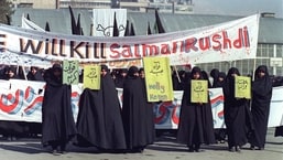 Mulheres iranianas são vistas segurando faixas com os dizeres 'Holly Koran' e 'Mate Salman Rushdie' durante uma manifestação contra o escritor britânico Salman Rushdie em Teerã. 