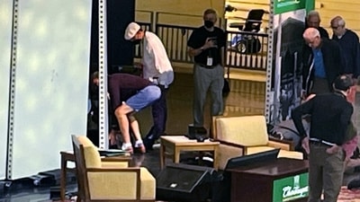 Author Salman Rushdie, behind screen left, is tended to after he was attacked during a lecture at the Chautauqua Institution in Chautauqua, New York. (AP)