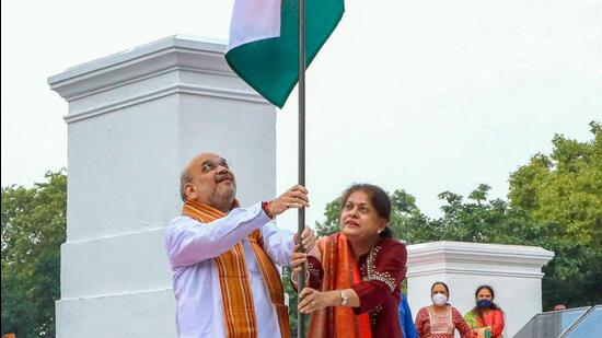 Union minister Amit Shah and his wife, Sonal Shah, hoist the Tricolour at their residence in New Delhi on Saturday. (PTI)