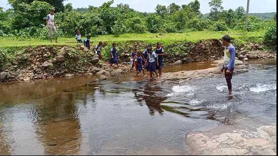 Students helped to cross the river in Shahapur. Students from tribal hamlets in Shahapur miss school due to overflowing river. (HT PHOTO)