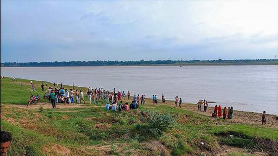 People gather along the banks of Yamuna river where a boat capsized in Uttar Pradesh’s Banda district on August 11. (PTI Photo)