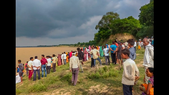 People gather near the banks of the Yamuna river where a boat capsized in Uttar Pradesh’s Banda on August 11. (PTI Photo)