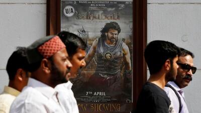 People walk past a poster of an Indian movie Baahubali: The Beginning outside a movie theatre in New Delhi, India, on April 12, 2017. (REUTERS) People walk past a poster of an Indian movie Baahubali: The Beginning outside a movie theatre in New Delhi, India, on April 12, 2017. (REUTERS)