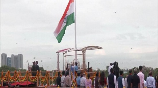 PM Modi hoisted the national flag wearing a traditional white kurta and churidar paired with a blue jacket and black shoes. Last year, he wore a saffron turban with red patterns and a long pink trail.(ANI)