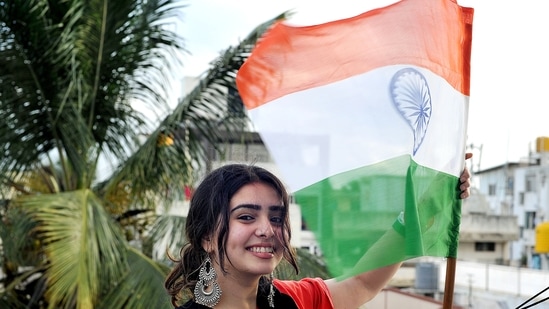 A student hoists the tricolor at her residence during 'Har Ghar Tiranga' campaign to commemorate the 75th anniversary of India’s Independence, in Bengaluru. (ANI Photo)