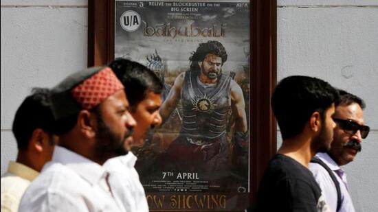 People walk past a poster of an Indian movie Baahubali: The Beginning outside a movie theatre in New Delhi, India, on April 12, 2017. (REUTERS)