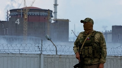 A serviceman with a Russian flag on his uniform stands guard near the Zaporizhzhia Nuclear Power Plant outside the Russian-controlled city of Enerhodar in Zaporizhzhia region, Ukraine. (REUTERS)