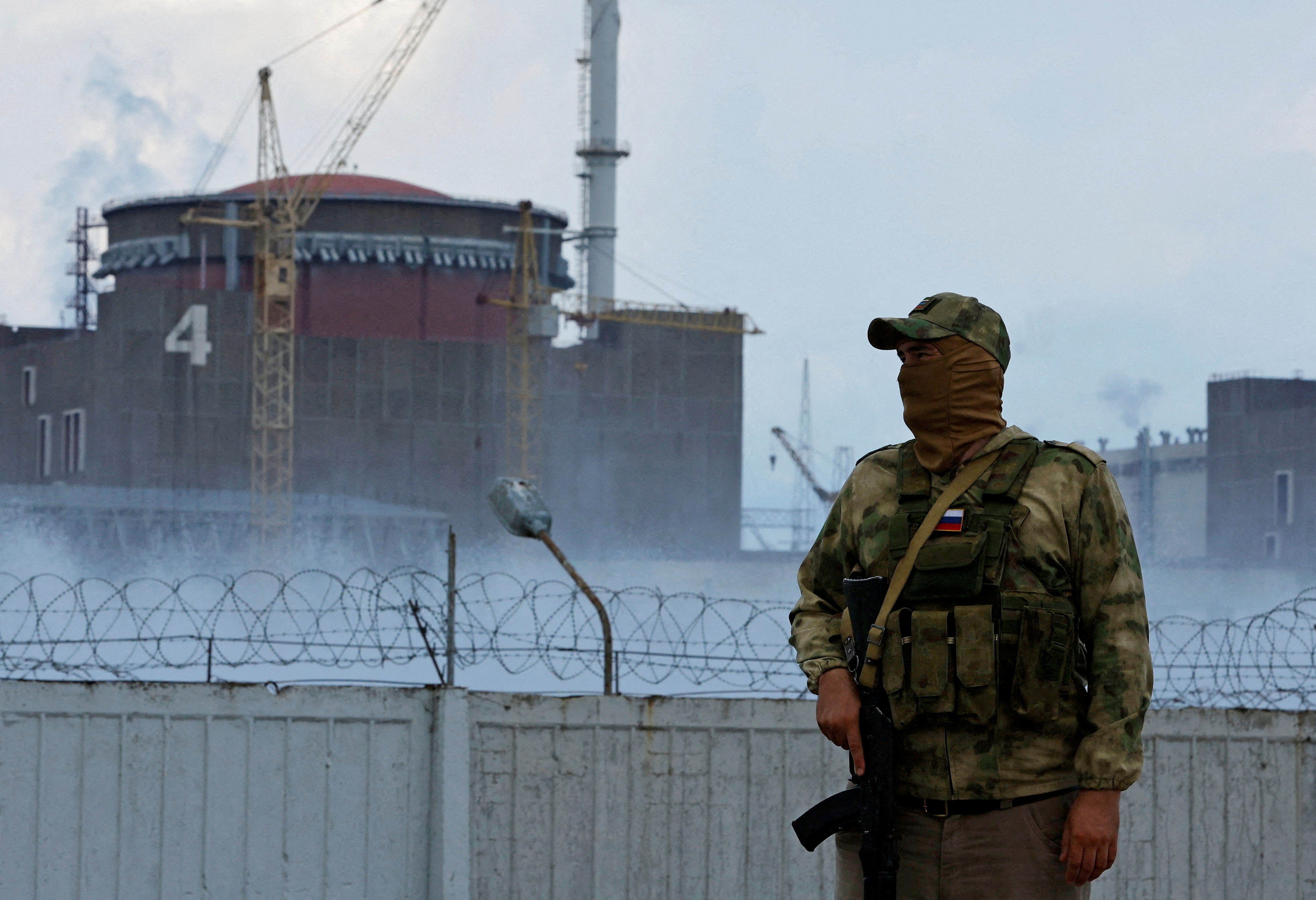 A serviceman with a Russian flag on his uniform stands guard near the Zaporizhzhia Nuclear Power Plant outside the Russian-controlled city of Enerhodar. (Reuters file photo)