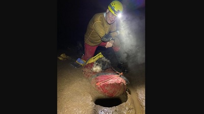 The image shows one of the &nbsp;men rescuing the dog trapped inside a cave. (Facebook/@Rick Haley)