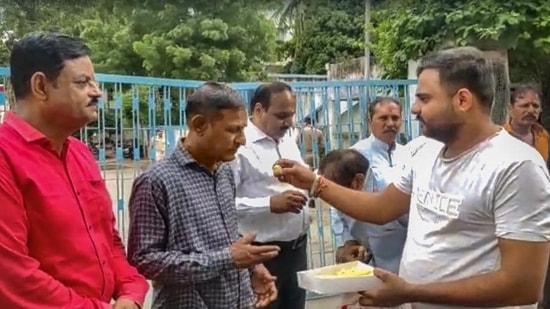 A man offers sweets to people convicted for rape and murder in the Bilkis Bano case of the 2002 post-Godhra riots, after they came out of the Godhra sub-jail after the Gujarat government allowed their release under its remission policy, in Godhra, Monday, Aug. 15, 2022. (PTI Photo)(