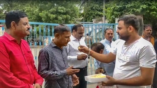 A man offers sweets to people convicted for rape and murder in the Bilkis Bano case of the 2002 post-Godhra riots, after they came out of the Godhra sub-jail.(PTI)