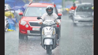 A scooterist caught in the rain in Sector 20, Chandigarh. (Keshav Singh/HT)