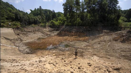 Gan Bingdong walks through the basin of a community reservoir near his farm that ran nearly empty after its retaining wall started to leak and hot weather and drought conditions accelerated the loss of water, in Longquan village in southwestern China's Chongqing Municipality, on Saturday. (AP)