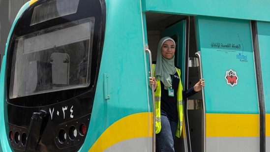 Suzanne Mohamed, an Egyptian woman metro train driver, poses through the entrance of a life-size train simulator at Adly Mansour station in the capital Cairo.(AFP)