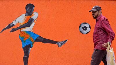 A pedestrian walks past a mural of a footballer playing a shot outside a soccer ground in Mumbai on August 22, 2022 (AFP) A pedestrian walks past a mural of a footballer playing a shot outside a soccer ground in Mumbai on August 22, 2022 (AFP)