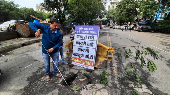 Rahul Pingle, a resident of Thane, put up a board alerting the motorists of an eight-foot deep pothole at Gurudwara Service Road in Thane. (PRAFUL GANGURDE/HT PHOTO)
