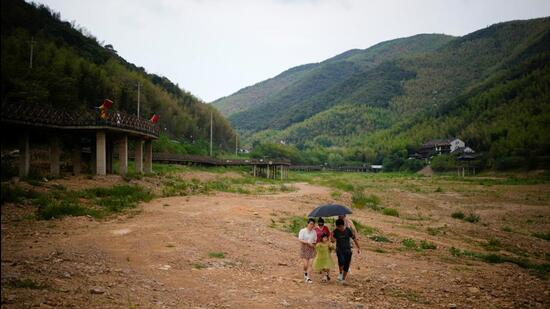 People walk on a dried-up bed of a reservoir, amid hot temperatures, while many regions from southwest to east of the country along the Yangtze river have been experiencing weeks of record-breaking heatwave in Changxing, Zhejiang province, China. (REUTERS)