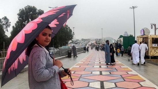 A woman walks with an umbrella along a promontory in al-Namas in Saudi Arabia's Asir province, on August 16, 2022. - As Saudi Arabia swelters in temperatures up to 50 degrees Celsius, some are escaping to the "City of Fog" -- a mountainous oasis of cool where warm clothing is needed even in summer. (Photo by Rania SANJAR / AFP)(AFP)