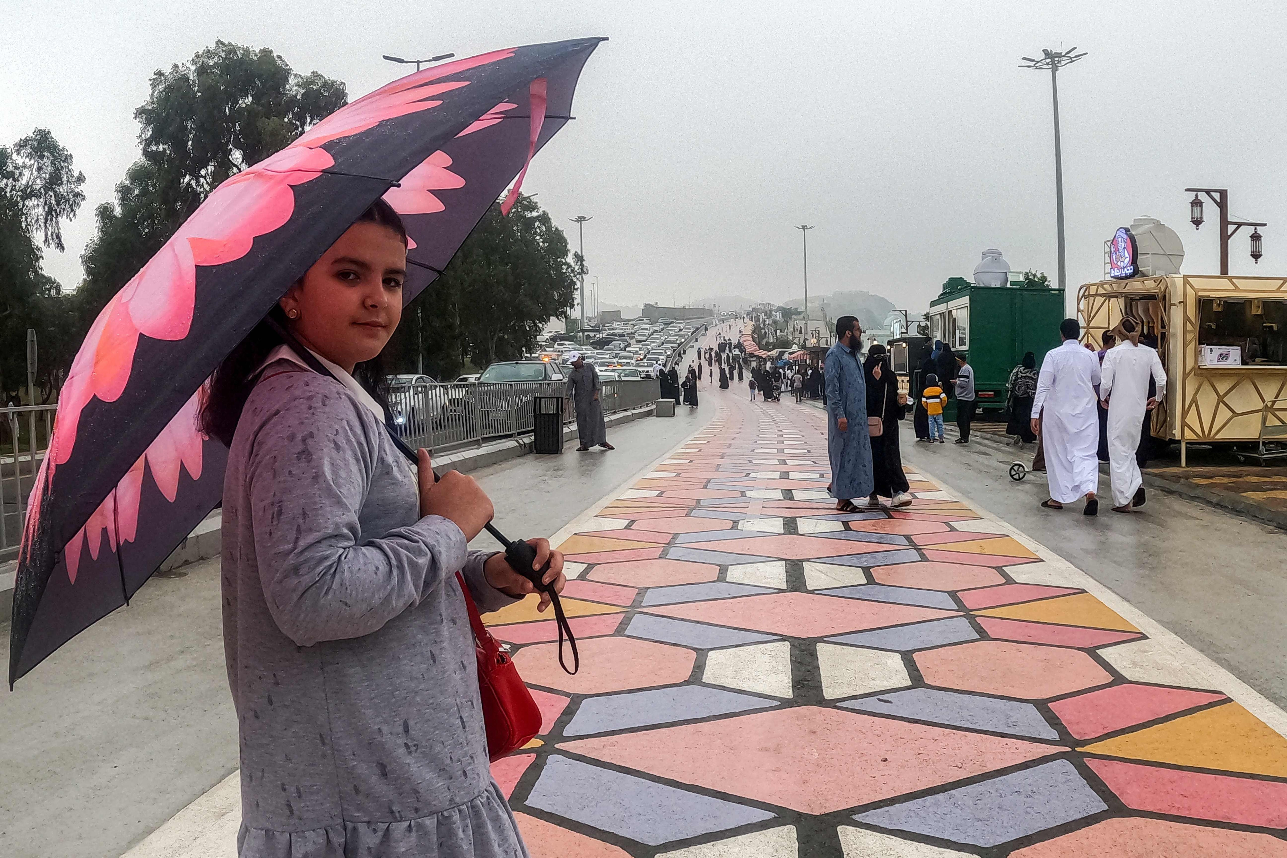 A woman walks with an umbrella along a promontory in al-Namas in Saudi Arabia's Asir province, on August 16, 2022. - As Saudi Arabia swelters in temperatures up to 50 degrees Celsius, some are escaping to the "City of Fog" -- a mountainous oasis of cool where warm clothing is needed even in summer. (Photo by Rania SANJAR / AFP) (AFP)