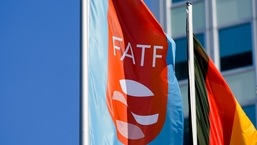 A flag emblazoned with the Financial Action Task Force (FATF) logo flutters in the wind next to the German flag during a task force meeting at the Congress Center in Berlin, Germany.