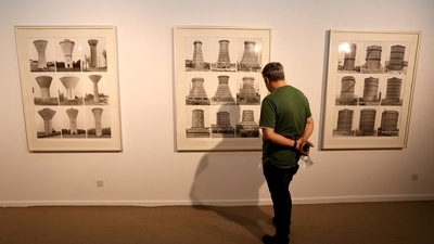 A visitor looks at artwork by German artists Bernd and Hilla Becher, a collaborative duo, best known for their extensive series of photographic images, or typologies, of industrial buildings and structures, often organised in grids. (AFP)