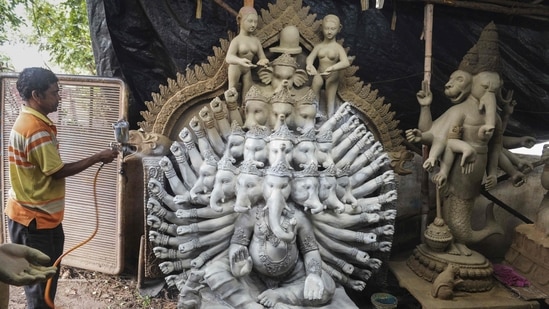 An artisan sprays paint on eco-friendly idols of the Hindu god lord Ganesha made with mud, jute and bamboo to reduce water pollution during the immersion rituals ahead of the Ganesh Chaturthi festival, at a workshop on the outskirts of Hyderabad.(AFP)