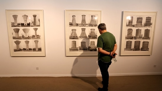 A visitor looks at artwork by German artists Bernd and Hilla Becher, a collaborative duo, best known for their extensive series of photographic images, or typologies, of industrial buildings and structures, often organised in grids.(AFP)
