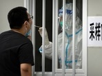 A worker wearing a protective suit swabs a man's throat for a Covid-19 test at a coronavirus testing site in Beijing. A worker wearing a protective suit swabs a man's throat for a Covid-19 test at a coronavirus testing site in Beijing.