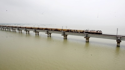 A train runs on a railway bridge as the water level of the Ganga river rises due to heavy rainfall, in Prayagraj on Friday. (ANI Photo) A train runs on a railway bridge as the water level of the Ganga river rises due to heavy rainfall, in Prayagraj on Friday. (ANI Photo)