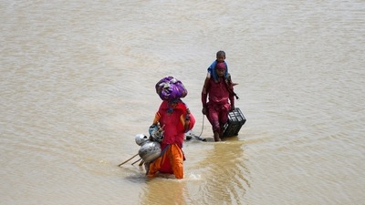 A family with their belongings wade through rain waters following rains and floods in Pakistan. (REUTERS)