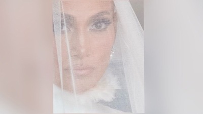 On Tuesday, the famous singer and actress Jennifer Lopez uploaded a picture of herself wearing a white veil to Instagram. The caption stated, "First peek at my wedding looks at OnTheJLo.com." It goes without saying that she looked ethereal in the close-up photo she shared of herself as a bride. Jennifer may be seen in the photo with smokey eyes, nude lips, and her hair pulled back neatly, even if just her shrouded face is visible. (Instagram/JenniferLopez) On Tuesday, the famous singer and actress Jennifer Lopez uploaded a picture of herself wearing a white veil to Instagram. The caption stated, "First peek at my wedding looks at OnTheJLo.com." It goes without saying that she looked ethereal in the close-up photo she shared of herself as a bride. Jennifer may be seen in the photo with smokey eyes, nude lips, and her hair pulled back neatly, even if just her shrouded face is visible. (Instagram/JenniferLopez)