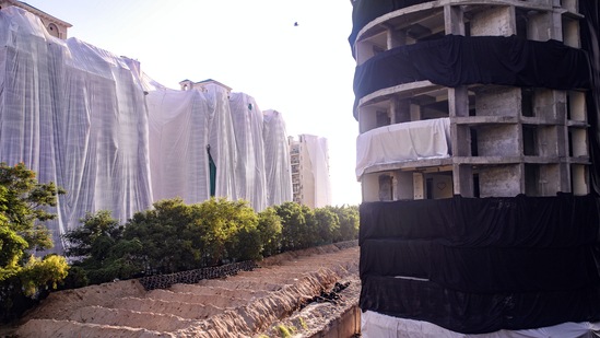 Buildings of a society near Supertech's 40-storey twin towers being covered ahead of the towers' scheduled demolition on August 28.(PTI)