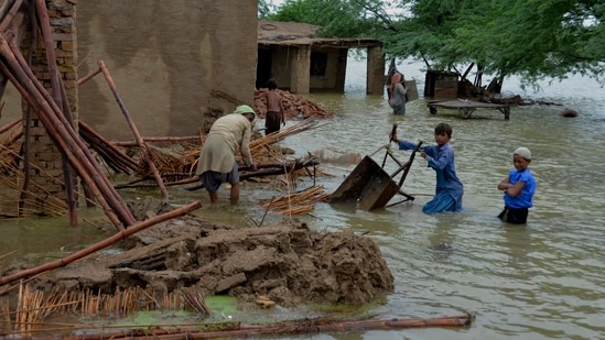 Una familia recupera artículos utilizables de una casa dañada por las inundaciones en Jaffarabad, un distrito en la provincia suroccidental de Baluchistán en Pakistán. (AP)