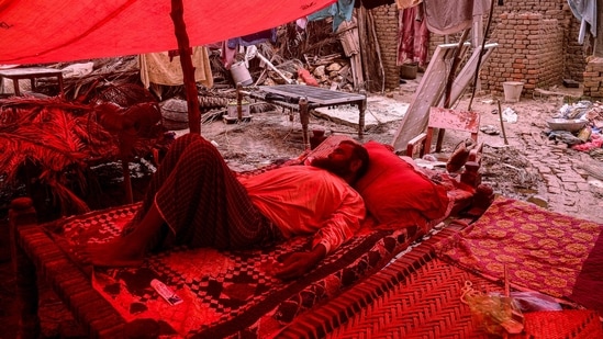 Un hombre duerme dentro de una tienda de campaña improvisada cerca de una casa dañada después de que las fuertes lluvias azotaran la provincia de Sindh en Pakistán. (AFP)
